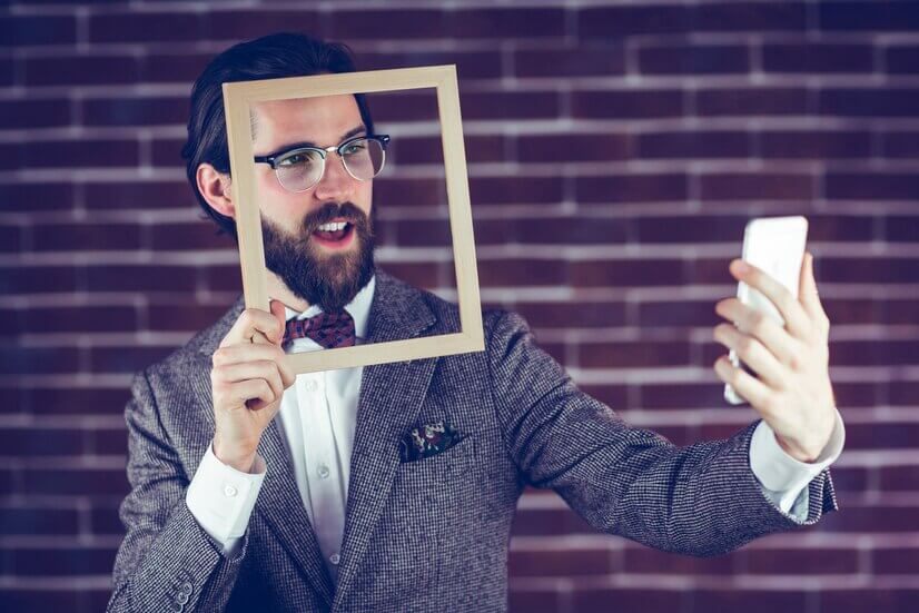 A man holding up a picture frame while taking a selfie.